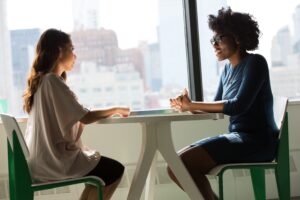 The silhouette of two women having an interview in front of a window.