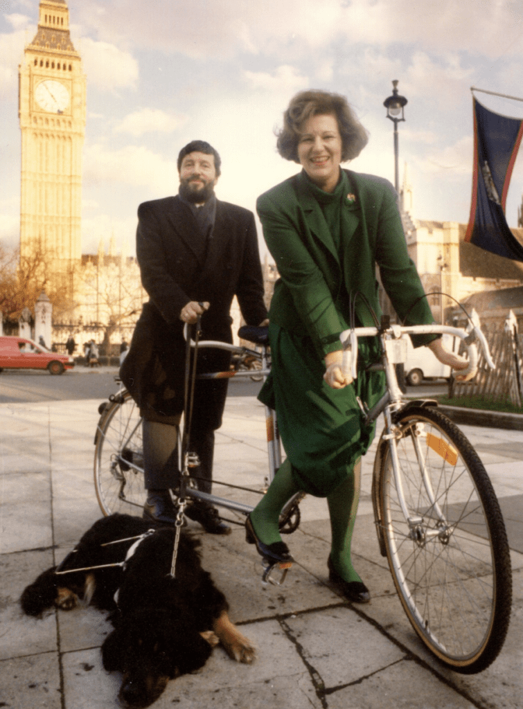 Lord Blunkett and the Baroness of Windermere on a tandem bike in front of Westminster