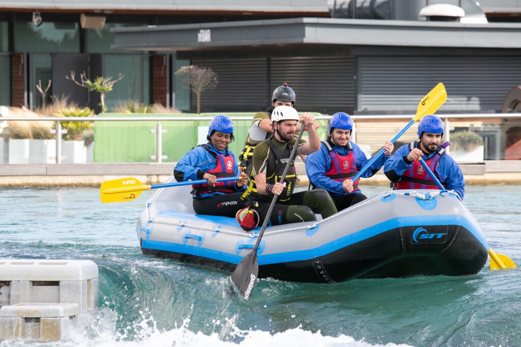 3 young men, and 2 young women in a white water raft about to start their adventure.